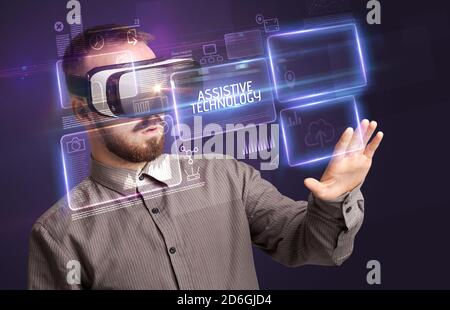 Businessman looking through Virtual Reality glasses with ASSISTIVE TECHNOLOGY inscription, new technology concept Stock Photo