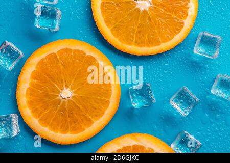 slices of orange  on a blue background, with ice around it and drops of water Stock Photo