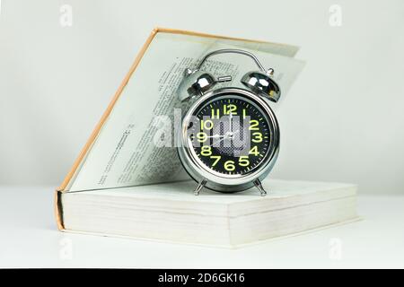Alarm clock on half open book isolated Stock Photo