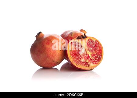 two pomegranate plus one cut in half isolated on white background Stock Photo
