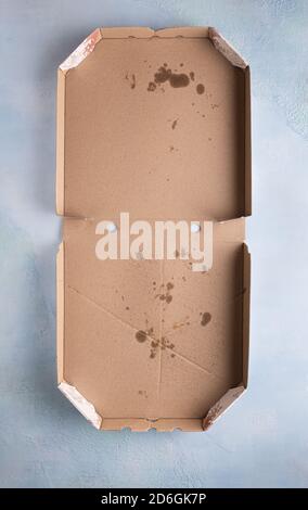 Mock up with used dirty opened empty pizza box made of paperboard with stains and crumbs inside on blue stone textured background. Vertical orientatio Stock Photo