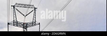 Steel power pylon construction with high voltage cables against cloudy sky. Wide banner for electric energy industry space for text on right side Stock Photo