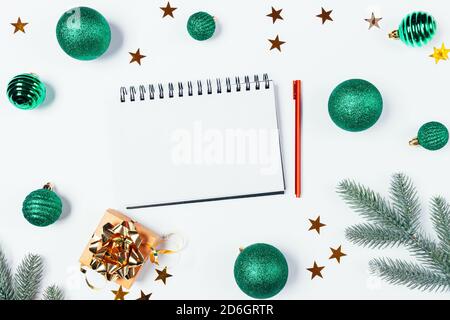 Christmas flat lay composition with blank notepad in center, christmas balls, gift box and fir branch on white table. Stock Photo