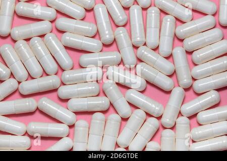 Top close up shot of white pills on pink background. Healthcare, medical and pharmaceutical concept. Stock Photo