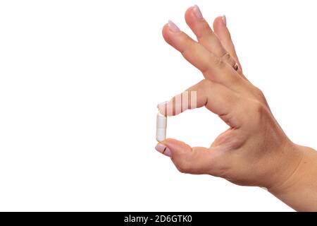 Female hand holding a white pill. Isolated on white background. Close up shot. Healthcare, medical and pharmaceutical concept. Stock Photo