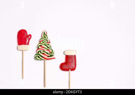 Sweet Christmas or New Year caramel candy in the form of a colored Christmas tree on a white background with golden tinsel. Banner, form for cards, pl Stock Photo