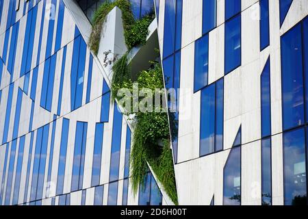 Modern Kö-Bogen building, designed by the New York star architect Daniel Libeskind, with „cuts“ in the facade for local green plants and grasses. Stock Photo