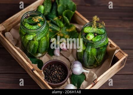 Fermentation of cucumbers in glass jars. Raw cucumbers, dill flowers, cherry leaf, horseradish leaf, spices and herbs on a tray, concept of organic an Stock Photo