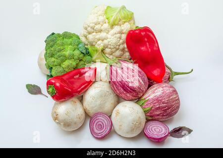 Vegetables and mushrooms on white background. Vegetarian dish ingredients - eggplants, champignons, paprika, onion, cauliflower and broccoli. Healthy Stock Photo