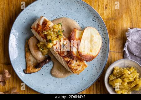 Pan fried halibut with mushroom velute, hazelnut pesto and potato crisps Stock Photo
