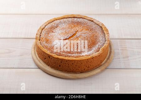 Whole round homemade cheesecake on wooden plate Stock Photo