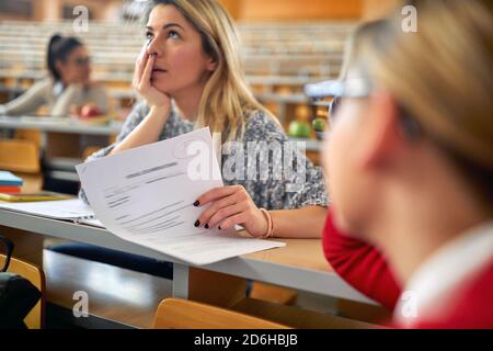 Female student in university amphitheater disappointed about low grade at the exam. Smart young people study at the college. Education, college, unive Stock Photo