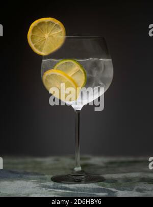 Gin and tonic cocktail drink indoors with ice, lemon and lime
