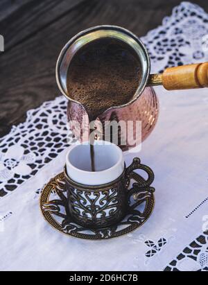 Turkish coffee cups with a glass of water on a wooden table with a white cloth photographed from above Stock Photo