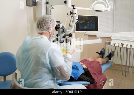 Dentist working with dental microscope and patient at modern dentist clinic Stock Photo