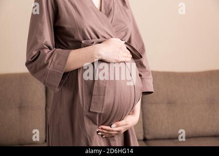 Pregnancy woman in beautiful dress standing on the home. Stock Photo