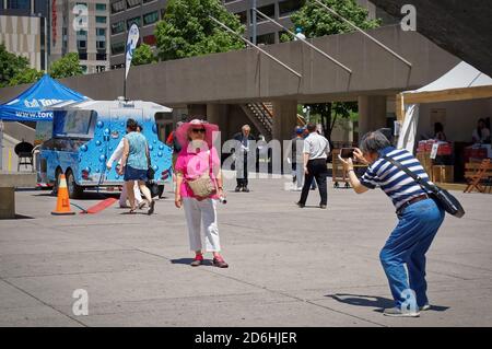 TORONTO, CANADA - 06 27 2016: A tourists couple taking a photo in the main square of Toronto Nathan Phillips Square to memorize their stay in major Stock Photo