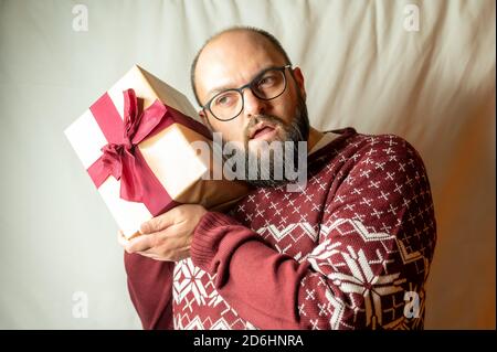 man carefully holds a present to his ear to find out what is inside Stock Photo