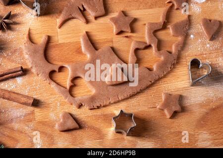 Cutting out shapes from dough to prepare gingerbread Christmas cookies Stock Photo