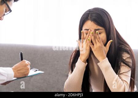 Portait of asian female patient talking to Psychotherapist doctor in medical clinic for consult about her mental health after stress strain from quara Stock Photo