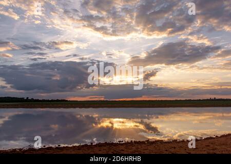 Sunset on the lake. Beautiful sunset behind the storm clouds before a thunder storm above the over lake landscape background. Dramatic sky with cloud Stock Photo