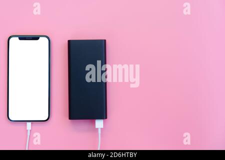 Smartphone charging with power bank on pink background. white screen or blank screen with clipping path for copy space. Flat lay Stock Photo