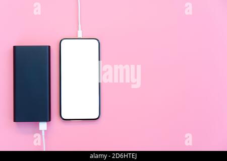 Smartphone charging with power bank on pink background. white screen or blank screen with clipping path for copy space. Flat lay Stock Photo