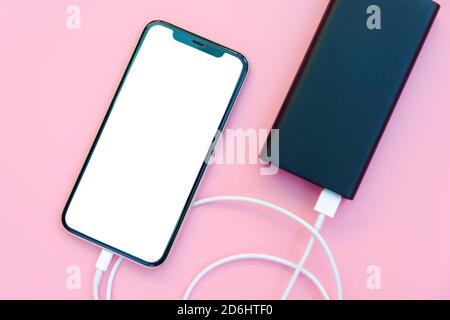 Smartphone charging with power bank on pink background. white screen or blank screen with clipping path for copy space. Flat lay Stock Photo