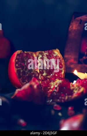 Close up of pomegranate fruit in dark food with ancient chandelier with a candle Stock Photo