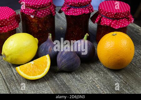 View on jars with homemade fig jam, citrus and orange fruit on wood table Stock Photo