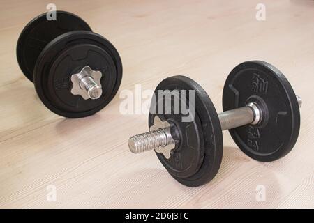 Dumbbells on wooden parquet floor.  Sports concept photo at home Stock Photo