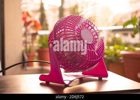 Pink mini fan working outdoors on wooden table Stock Photo