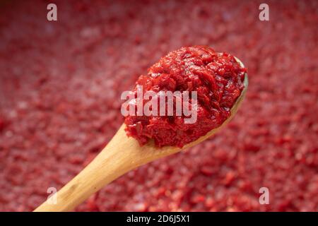 Pepper paste in wooden spoon on red background Stock Photo