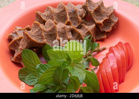 Turkish raw meatball (Cig kofte), Turkish Spicy Meatless with tomato and mint food concept Stock Photo