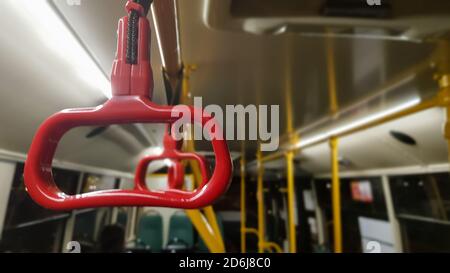 Red hanging handrail on the ceiling for standing passengers in transport. Modern suburban and urban public transport. Empty bus Stock Photo