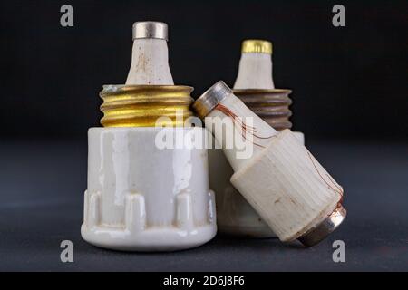 Old ceramic electric fuses. Accessories for the repair of the power network. Dark background. Stock Photo
