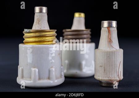 Old ceramic electric fuses. Accessories for the repair of the power network. Dark background. Stock Photo