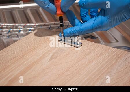 Door hinge installation. Male hand fixing,  repairing hing in the kitchen cupboard,  home small repairs. Stock Photo