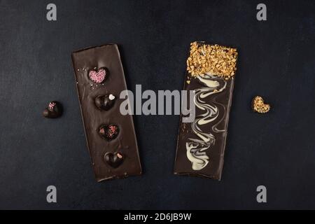 Dark chocolate bars with decorations isolated on a dark background. Top view, flat lay. Stock Photo