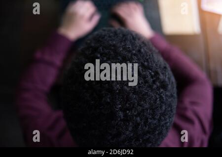 Young black male  developer sitting in pizza restaurant, drinking coffee or  tea and working with laptop. Stock Photo