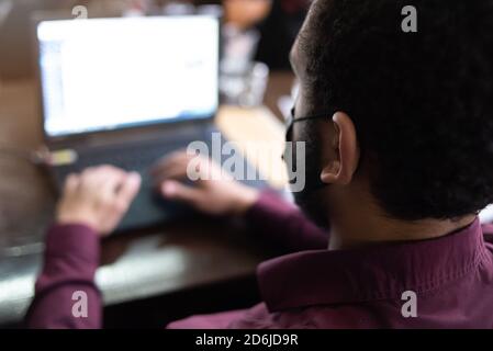 African businessman or developer wearing surgical face mask in the restaurant and typing on laptop - concept on new normal everyday lifestyle and peop Stock Photo