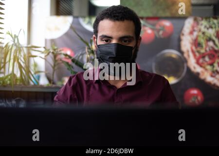 African businessman or developer wearing surgical face mask in the restaurant and typing on laptop - concept on new normal everyday lifestyle and peop Stock Photo