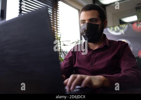 African businessman or developer wearing surgical face mask in the restaurant and typing on laptop - concept on new normal everyday lifestyle and peop Stock Photo