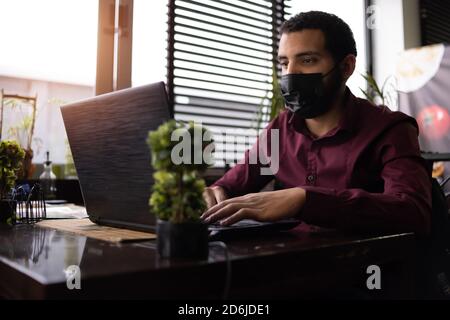 African businessman or developer wearing surgical face mask in the restaurant and typing on laptop - concept on new normal everyday lifestyle and peop Stock Photo