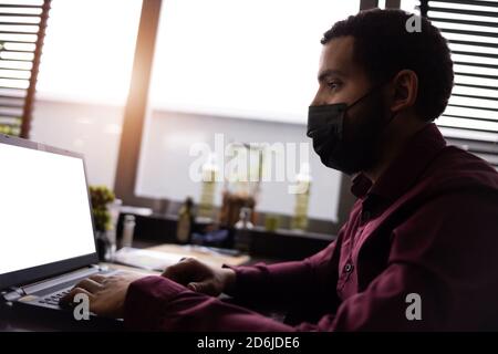 African businessman or developer wearing surgical face mask in the restaurant and typing on laptop - concept on new normal everyday lifestyle and peop Stock Photo