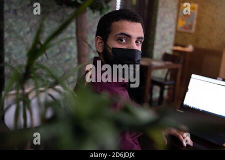 African businessman or developer wearing surgical face mask in the restaurant and typing on laptop - concept on new normal everyday lifestyle and peop Stock Photo