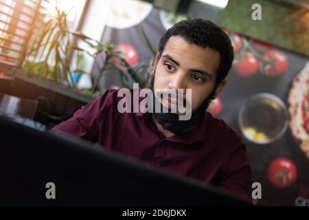 African businessman or developer wearing surgical face mask in the restaurant and typing on laptop - concept on new normal everyday lifestyle and peop Stock Photo
