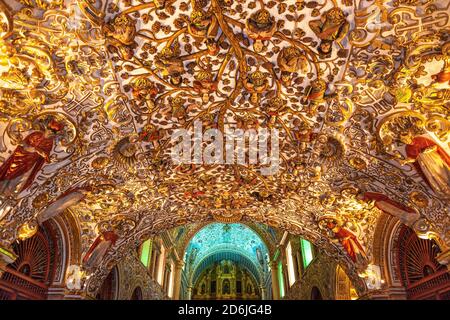 The morning light shining inside the Santo Domingo church at sunrise with its intricate gold leaf decorations, Oaxaca, Mexico. Stock Photo