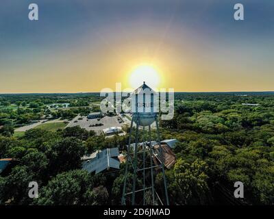 Handsome view of the iconic water tower in downtown Gruene, TX with the sun setting behind it. Famous Gruene Hall and Grist Mill restaurant are below. Stock Photo