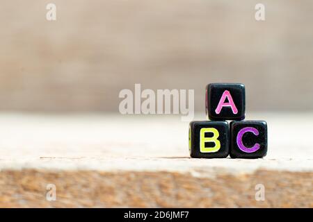 Black bead with color letter in word abc on wood background Stock Photo